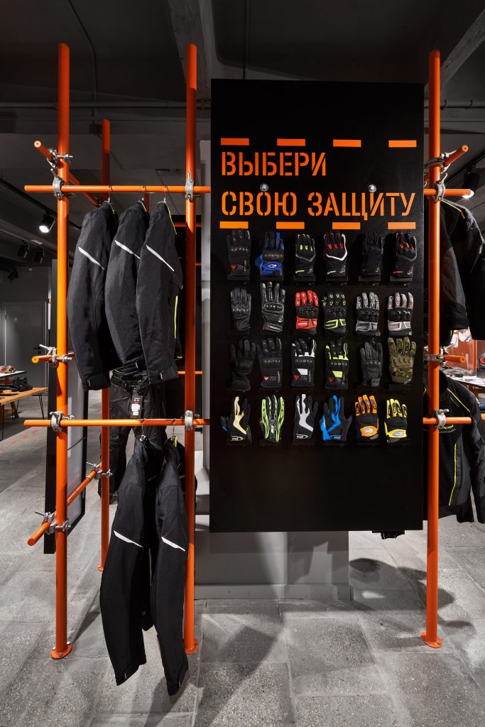 Оранжевые металлические конструкции для мотосалона в лофт дизайне. Торговое оборудование для мотоперчаток.